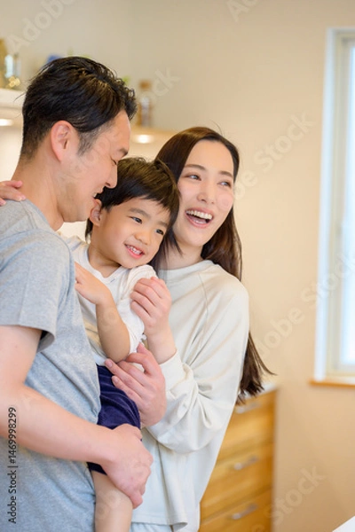 Obraz 父親が子どもを抱き上げて笑顔を交わす様子を母親が見守る微笑ましい朝の風景