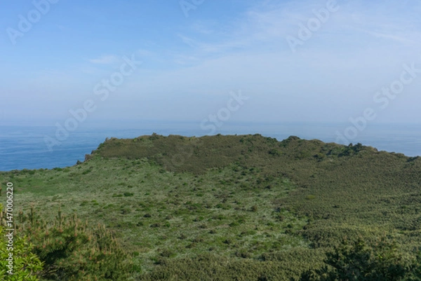 Obraz Seongsan Ilchulbong volcanic crater landscape, tranquil mood, representing Jeju, South Korea nature against a blue sky and ocean background 