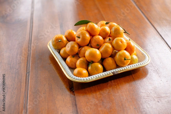 Fototapeta Stack of Mandarin oranges in a square tray on a wooden table