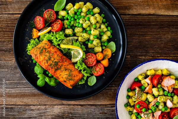 Obraz Seared salmon steak with gnocchi, green peas and tomatoes on wooden table	