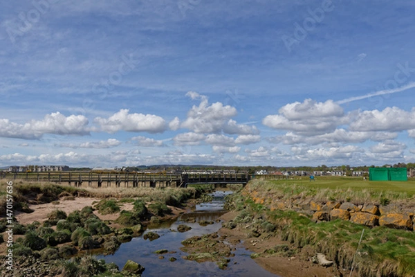 Fototapeta The Barry Burn wending its way through Carnoustie Links Golf Course with the old abandoned wooden Footbridge in the background.