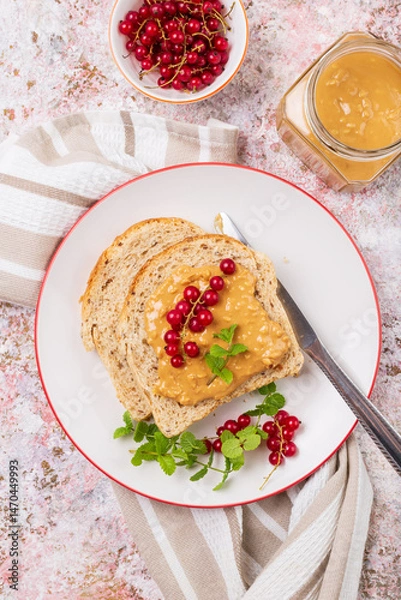 Fototapeta Whole grain sandwich with peanut butter and red currant top view