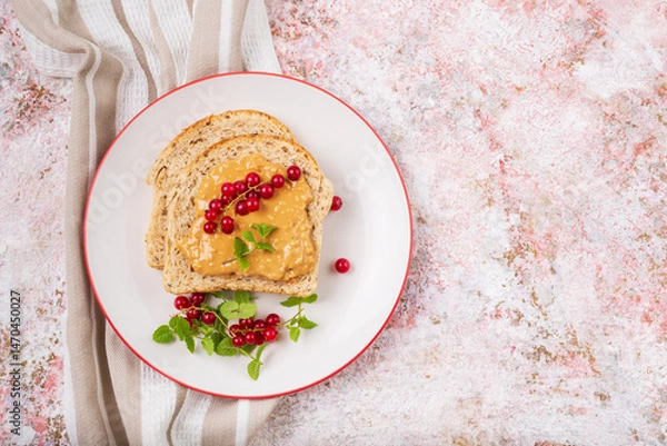 Fototapeta Whole grain sandwich with peanut butter and red currant top view with copy space
