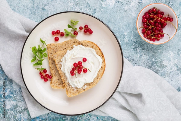 Fototapeta Breakfast with whole grain sandwich with cream cheese or cottage cheese, fresh mint and red berries on white plates top view