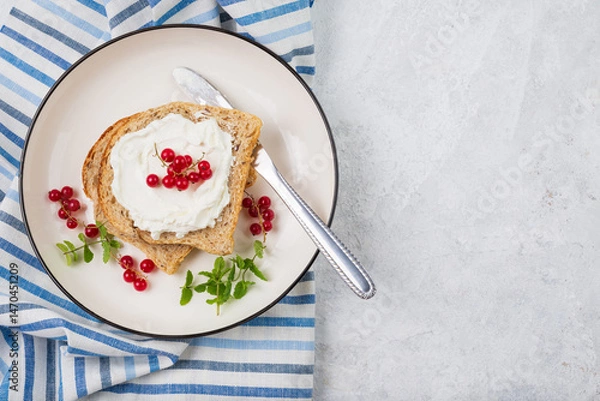 Fototapeta Whole grain sandwich with cream cheese or cottage cheese, mint and red currant on white plate top view with copy space