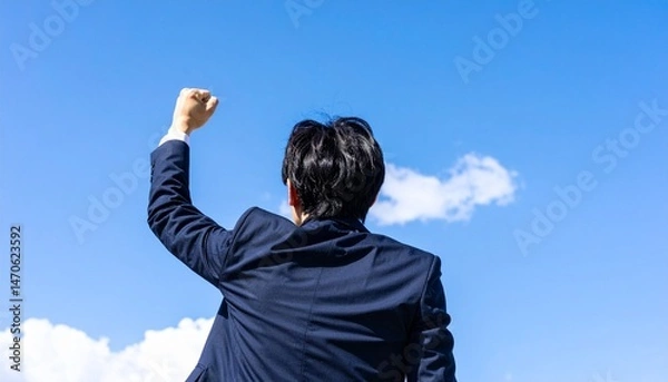 Fototapeta 青空を見上げてガッツポーズする若いビジネスマン
