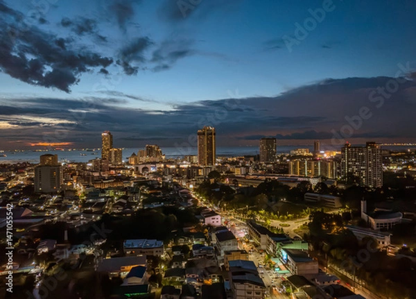 Fototapeta Evening skyline of a bustling coastal city with ships on the horizon during sunset