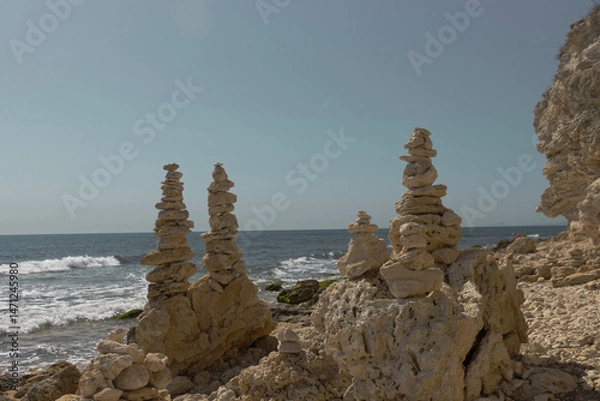Fototapeta A serene and artistic scene on the rocky beach of Nessebar along the Black Sea coast. Several carefully balanced stacks of light-colored stones rise from among larger rocks and pebbles.