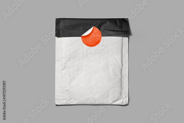 Fototapeta Crumpled white envelope sealed with a bright orange sticker and black flap, set on grey background. Great for branding mockups, mailing templates, or retro packaging design.