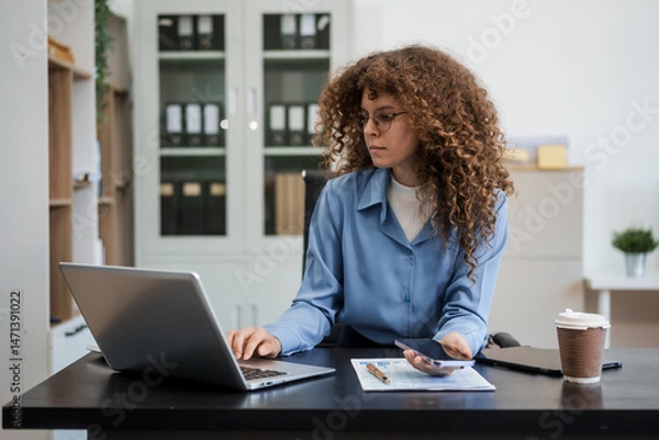 Obraz Confident Russian businesswoman sits indoors at her desk, dressed in formal attire,  paperwork and planning. Stylish and efficient, she manages tasks, notes ideas, and leads with professionalism.