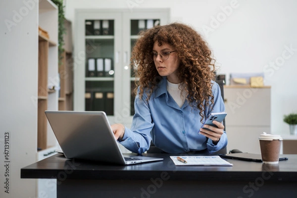 Obraz Confident Russian businesswoman sits indoors at her desk, dressed in formal attire,  paperwork and planning. Stylish and efficient, she manages tasks, notes ideas, and leads with professionalism.