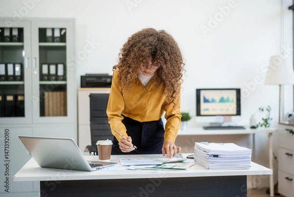 Obraz Confident Russian businesswoman sits indoors at her desk, dressed in formal attire,  paperwork and planning. Stylish and efficient, she manages tasks, notes ideas, and leads with professionalism.