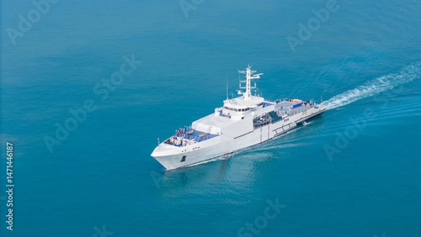 Obraz Aerial view of a modern patrol vessel sailing on calm turquoise sea, equipped with radar, deck equipment, and a helipad. Concept of maritime security, naval operations, and coast guard missions.