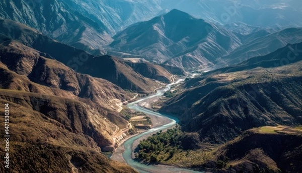 Fototapeta A flowing river carves its way through the mountains