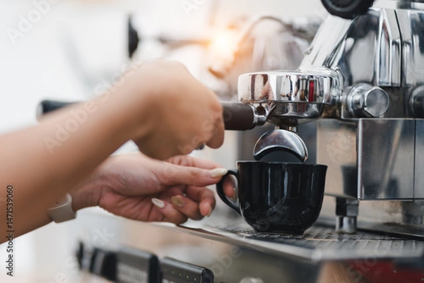 Fototapeta Barista hand making espresso coffee with professional machine, pouring fresh hot drink into black cup in cafe, morning routine, cozy atmosphere