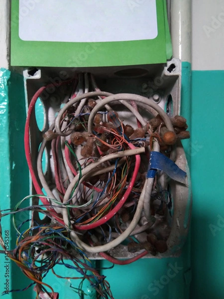 Obraz A tangled mess of wires is hanging from a wall