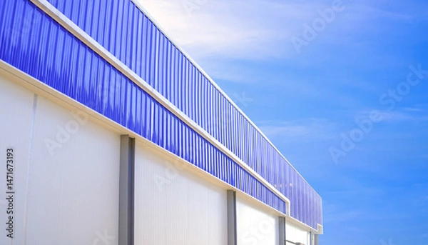 Fototapeta Freezer warehouse industrial factory building with corrugated aluminium and white sandwich panel isowall against blue sky background, exterior architecture in perspective side view