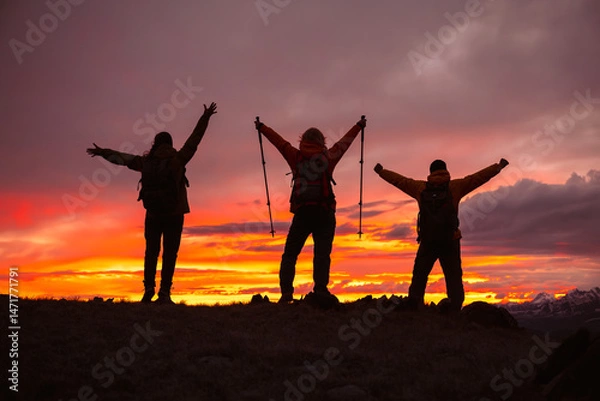 Obraz A small group of tourists celebrate reaching the top of a mountain against the backdrop of a colorful sunset