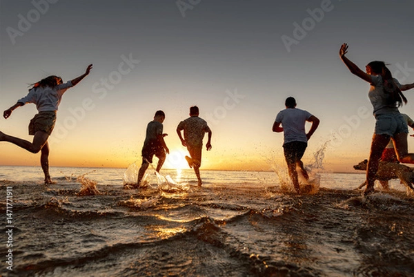 Obraz Group of happy young people running at the beach on beautiful summer sunset