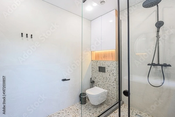Fototapeta Modern bathroom with glass shower, wall-mounted toilet, and terrazzo flooring. Clean lines and minimalist design