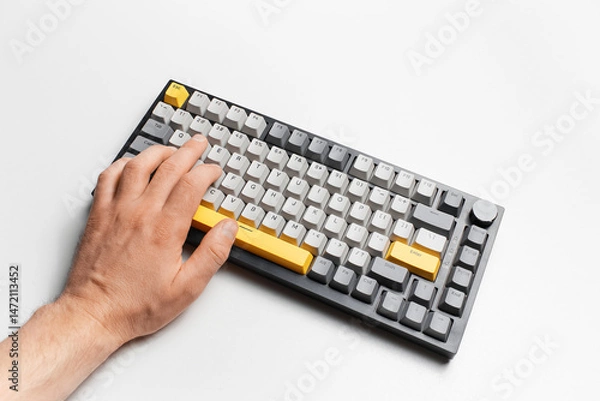 Fototapeta Top view of male hand typing on keyboard with grey and yellow key cap.