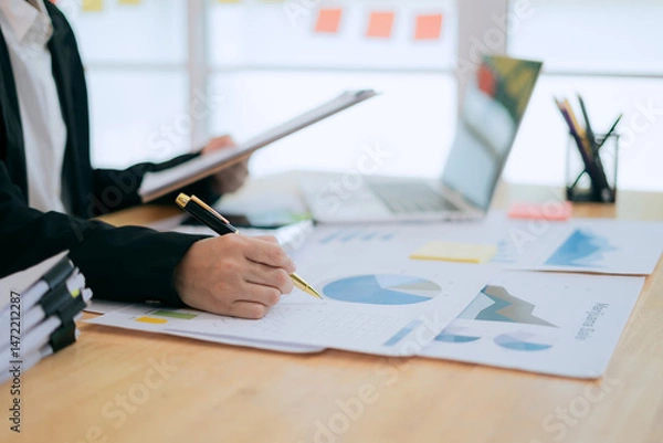 Fototapeta Asian female accountant businesswoman analyze using laptop to collect financial data in office. Business finance, tax and accounting concept.