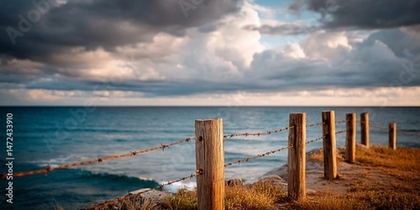 Obraz Barbed wire fence against dramatic sky