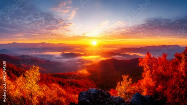 Fototapeta Vibrant sunrise over autumnal mountain range, mist-filled valleys, and fiery foliage