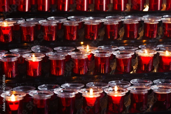Obraz Lots of prayer candles in glass candlesticks.