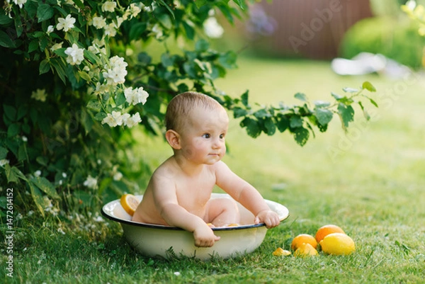 Fototapeta Baby Sitting In Basin Surrounded By Lemons