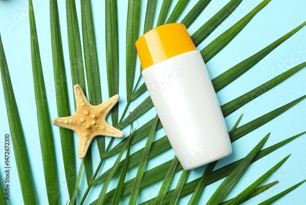Obraz Top view of SPF skin care bottle with palm leaves on blue background. Vacation concept