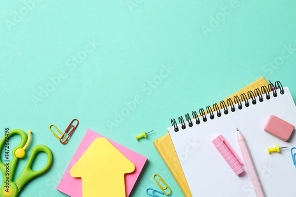 Obraz Assorted educational supplies including pen, notebooks, and stationery placed on a color surface