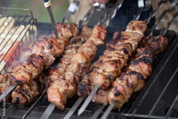Fototapeta Freshly cooked and fried pork shashlik strung on skewers lies on the grill and is ready for a treat.