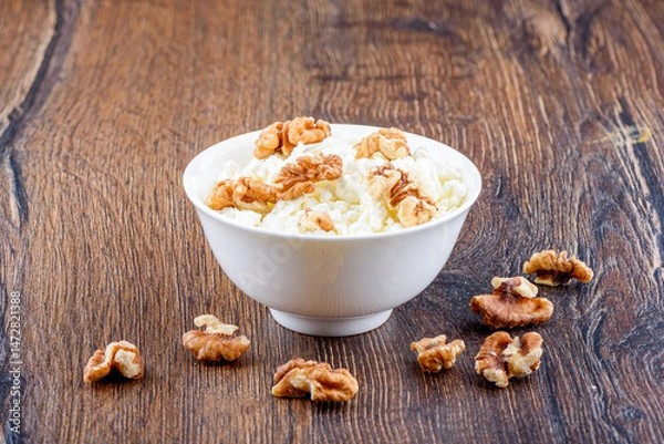 Obraz Fresh cottage cheese with walnuts in a white bowl.