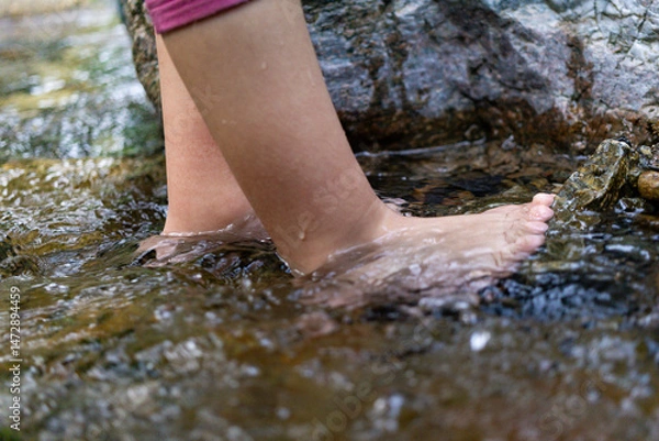 Obraz Toddler girl in nature with her feet in shallow stream water