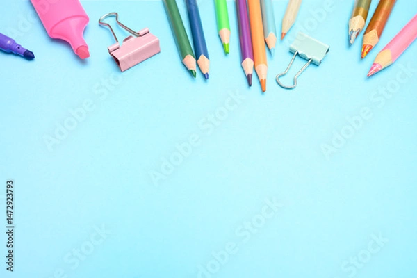 Fototapeta Flat lay of school stationery like pencils, clips, and sharpeners on blue background. Ideal for educational content, back to school promotions, and academic materials.