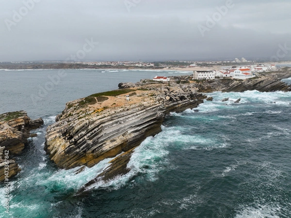Fototapeta Mid-height drone shot of cliff lines and ocean beside village of Baleal