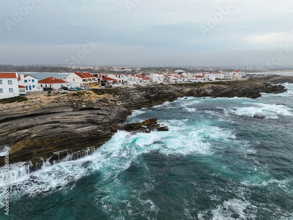 Fototapeta Coastal view of red-roofed buildings in Baleal surrounded by crashing surf