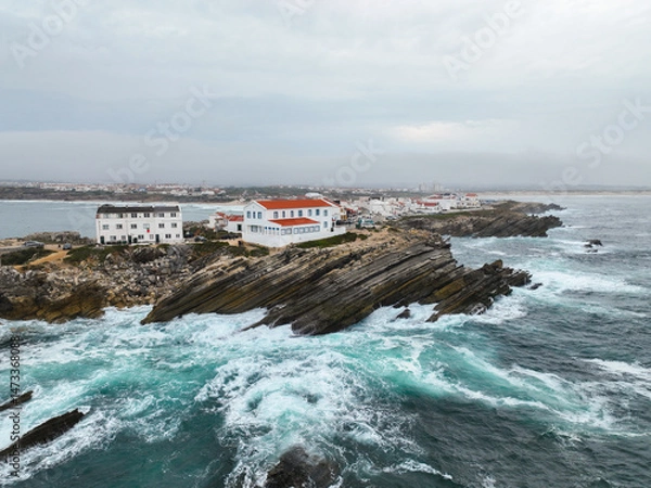Fototapeta Coastal view of red-roofed buildings in Baleal surrounded by crashing surf
