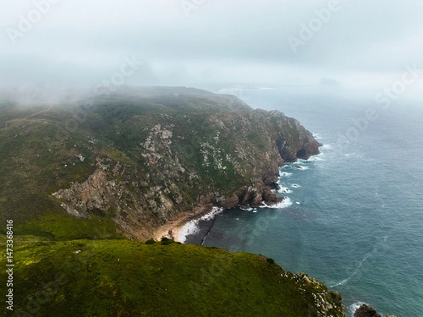 Fototapeta High-angle drone view of a hidden cove surrounded by steep green slopes