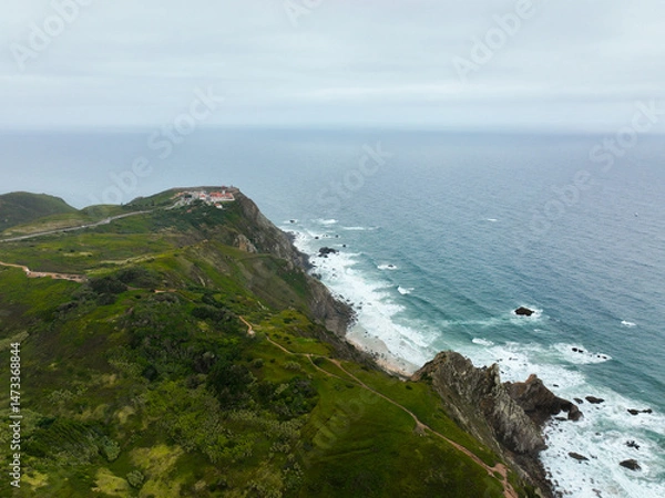 Fototapeta Drone image of lush hills and dirt trail heading to Cabo da Roca cliffs