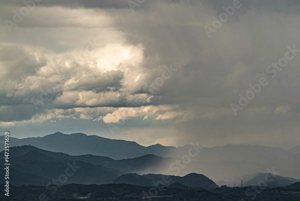 Fototapeta 重い雨雲から山の向こうに雨柱で土砂降りが降り注ぐ