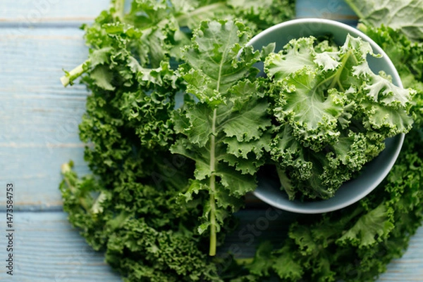 Fototapeta Fresh green Kale leaf salad vegetable in ceramic bowl on blue wooden background.