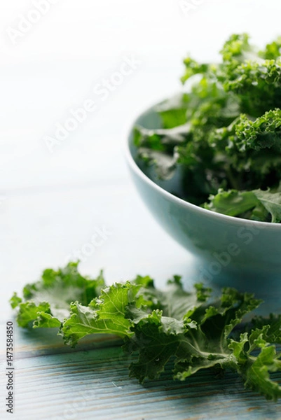 Fototapeta Fresh green Kale leaf salad vegetable in ceramic bowl on blue wooden background.