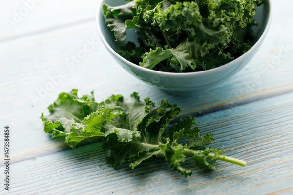 Fototapeta Fresh green Kale leaf salad vegetable in ceramic bowl on blue wooden background.