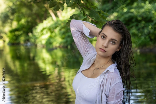 Obraz Moody portrait of beautiful brunette girl with wet hair posing in the river. Horizontally. 