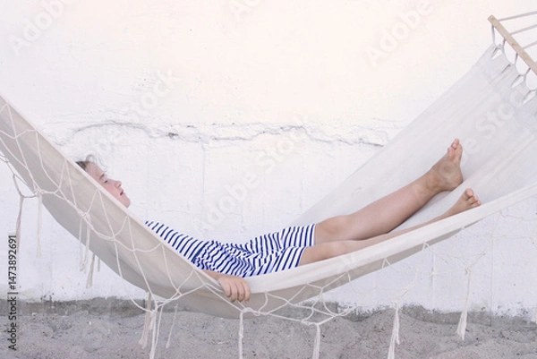 Fototapeta girl resting on shaded hammock on terrace