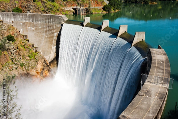 Fototapeta Water spills over the top of Englebright Dam on the Yuba River. A larger than normal snowpack in the Sierra Nevada Mountains has increased runoff into lakes and rivers in California.