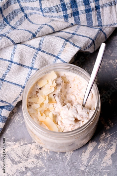 Fototapeta Healthy breakfast overnight oats with cocos and banana in a glass jar