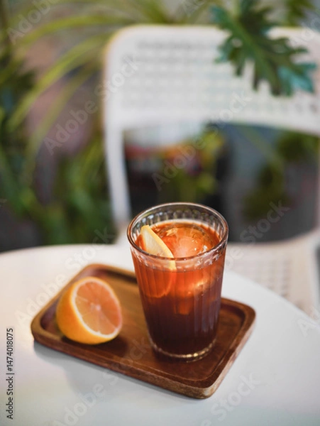 Fototapeta Craft Cola. A top view soft focus on a craft cola with round ice ball and a half of lemon on the side. Refreshment during summer. Vintage film grained filter.